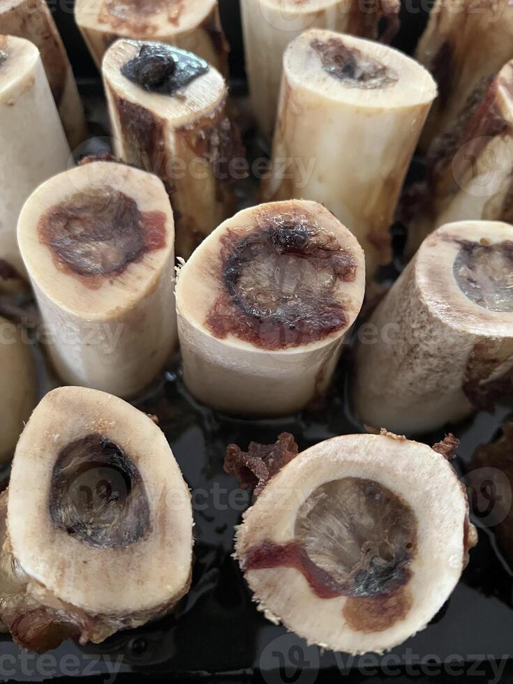 Macro shot of roasted bone marrow in baking tray. The roasted texture and bone color contrast with the black color of the tray. photo