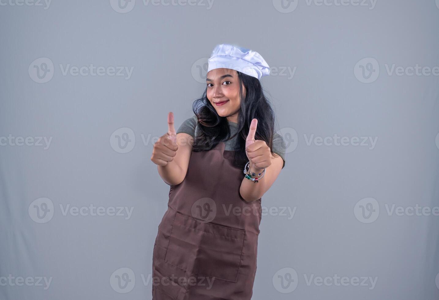 a woman in an apron and chef hat giving the thumbs up photo