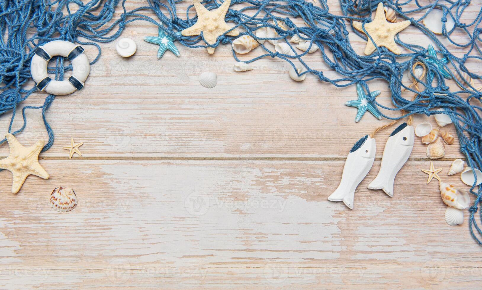 Fishing net, seashells, starfishes and fishes on rustic white wooden background creating a frame photo