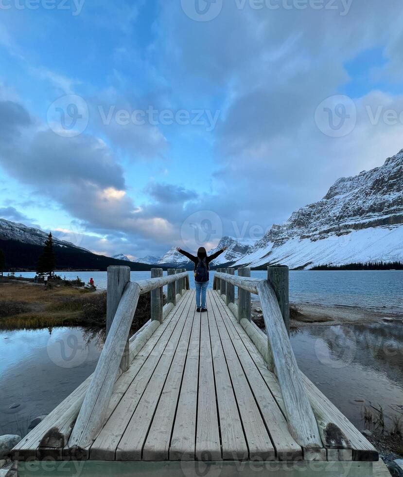Traveler Standing on Wooden Bridge Looking at Bow Lake, Bnaff National Park Canada photo