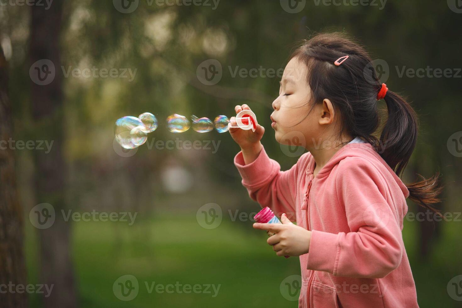 Young Girl Blowing Soap Bubbles in Park photo