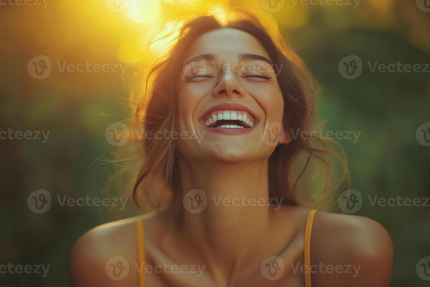 Happy woman smiling with eyes closed in golden sunlight photo