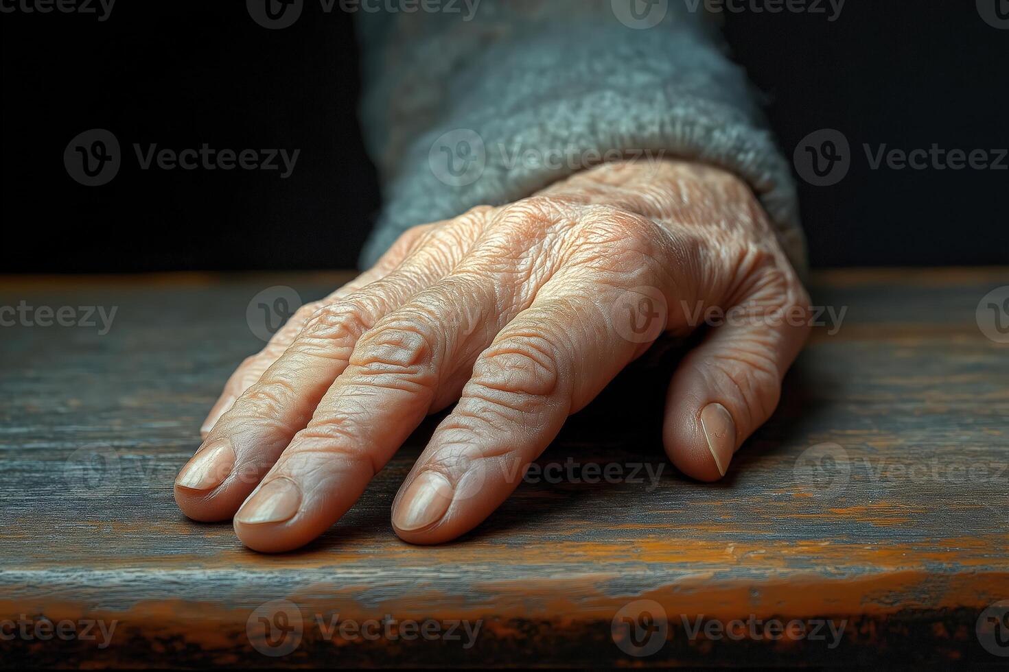 Senior hand resting on wooden table, showing signs of aging photo