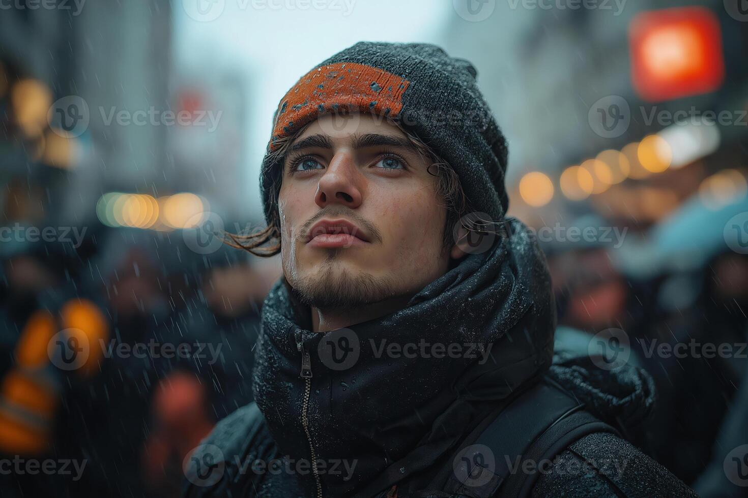 Young man looking up in the rain in city center photo