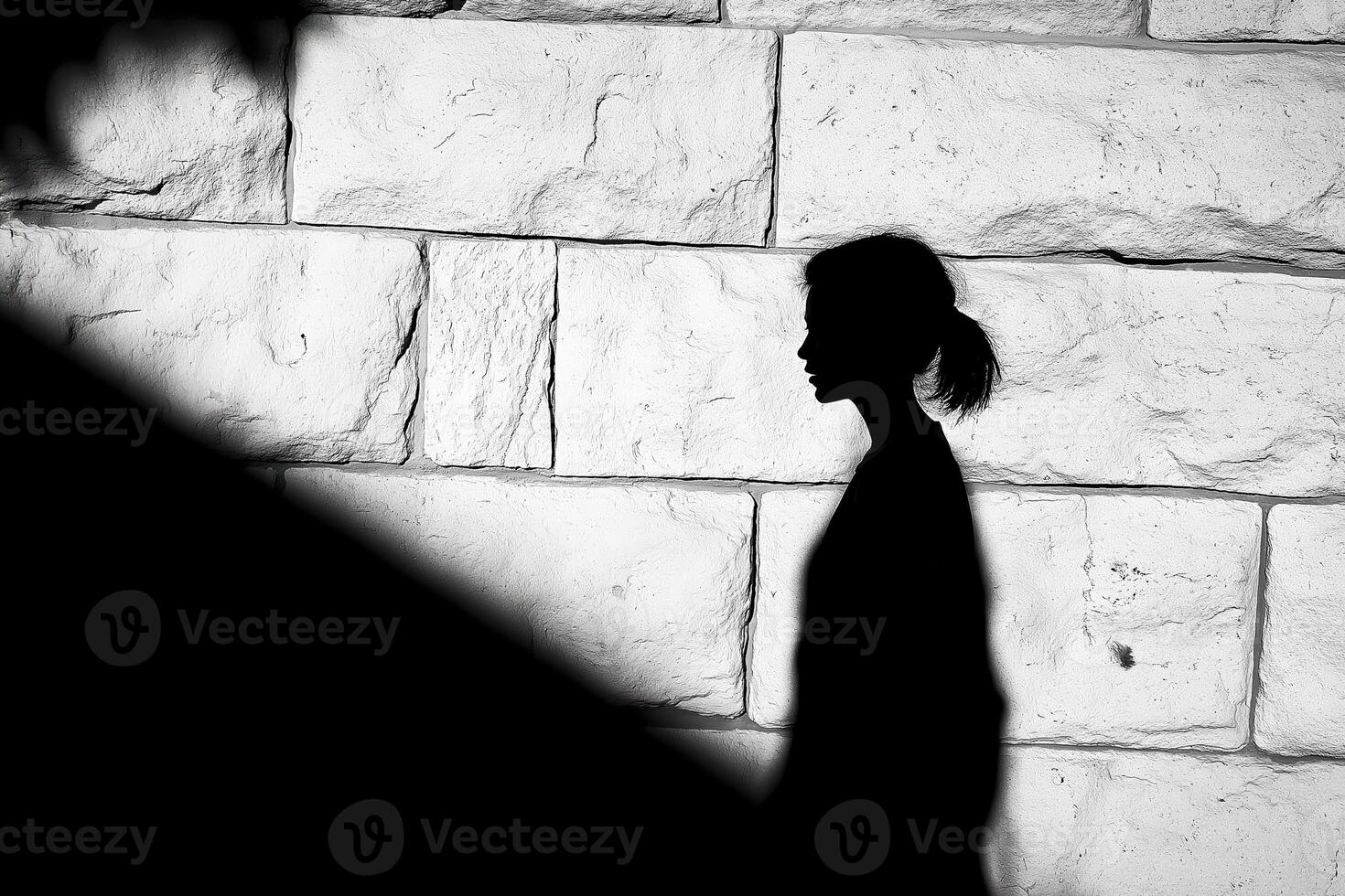 Silhouette of young woman walking by white brick wall photo
