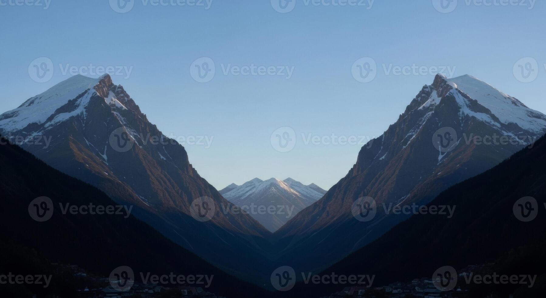 Symmetrical Mountain Peaks with Snow Caps and Deep Valley Shadows photo