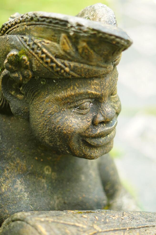 The face of a carved stone statue wearing a typical Balinese head covering udeng in close up mode photo