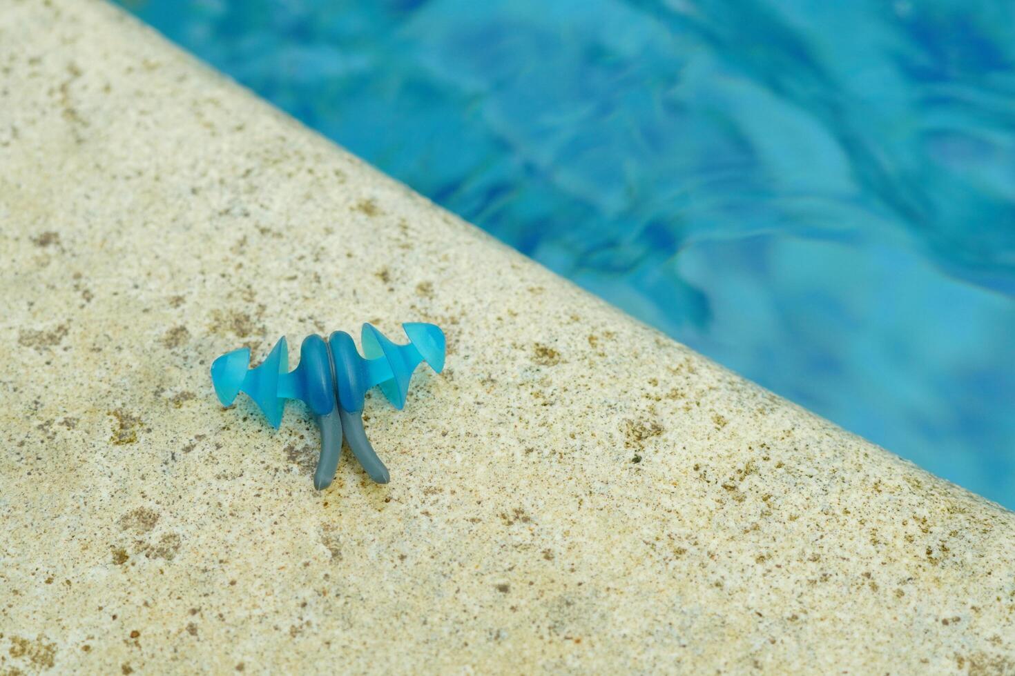 Earplugs for swimming that are on the edge of the pool with blue and clear water photo