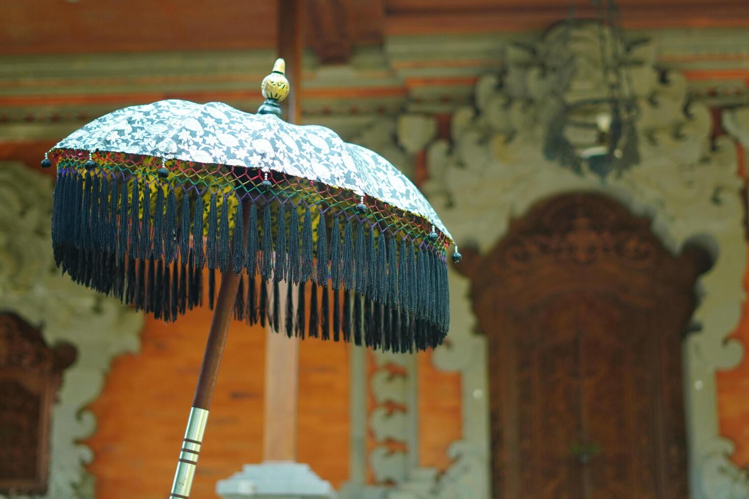 An umbrella made of typical Balinese cloth in front of a building with a typical Balinese style photo