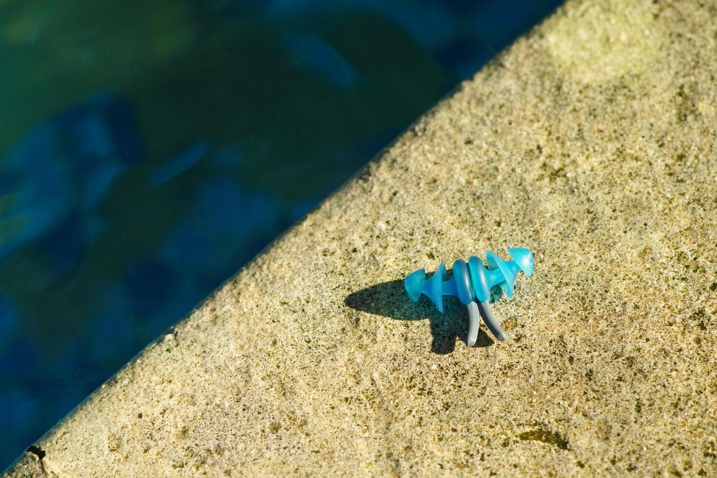 Earplugs for swimming that are on the edge of the pool and exposed to the morning sun photo