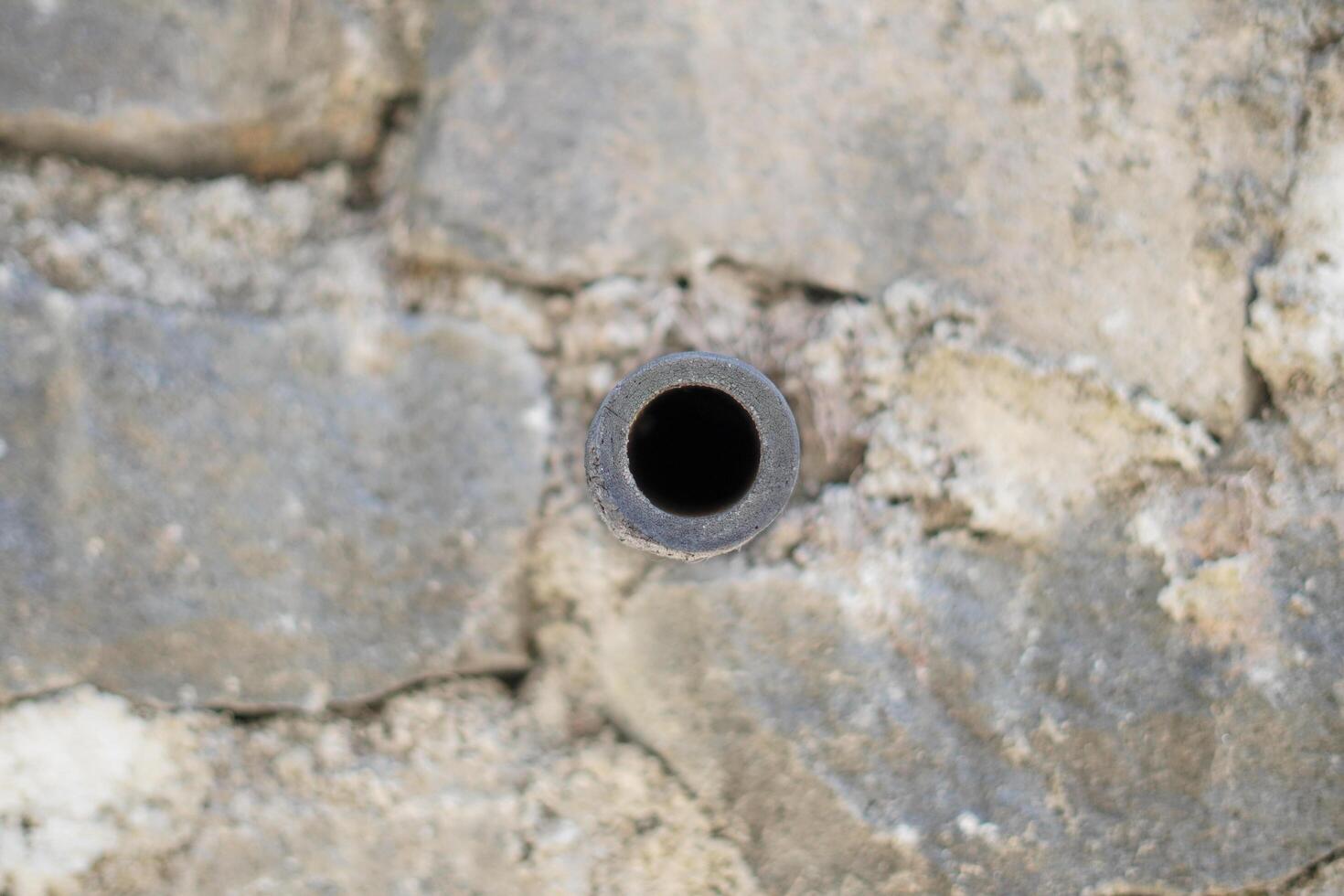 A small pipe in the middle of a wall made of piles of stones photo