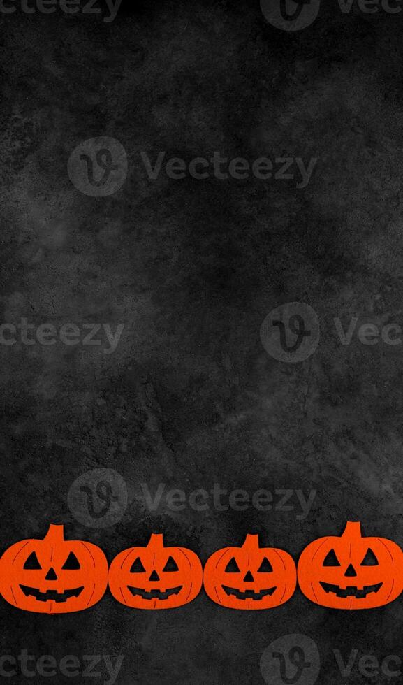 Vertical banner with pumpkins at bottom border against dark mystery concrete background. Halloween flat lay with place for text. Card or invitation for october 31. photo