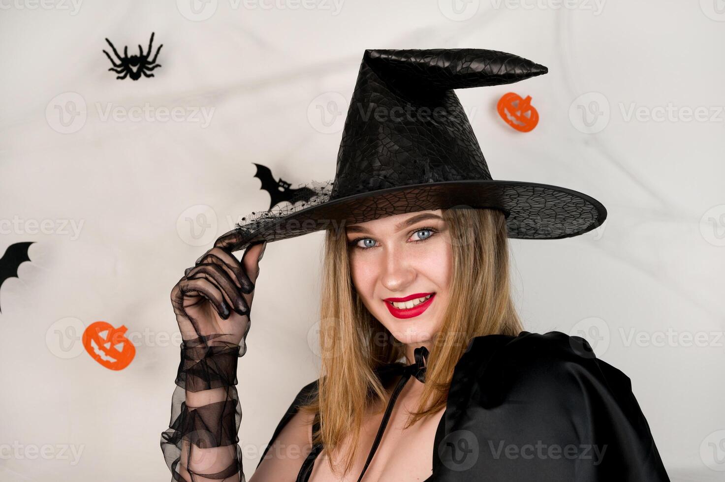 halloween witch against spooky background with spiders,web and bets smiling camera. October 31 trick or treat party photo