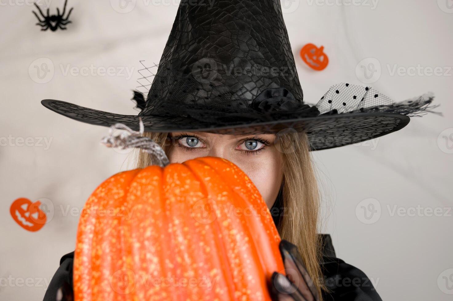 Mystery halloween background with witch looking from behind pumpkin. photo