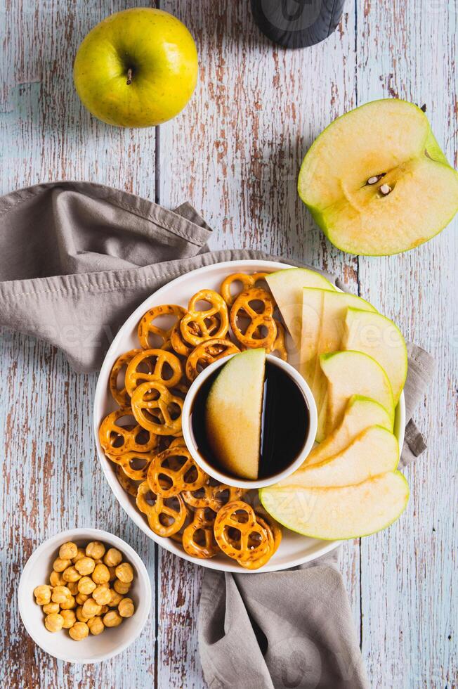 Crispy green apples and pretzels with miso caramel sauce on a plate top and vertical view photo