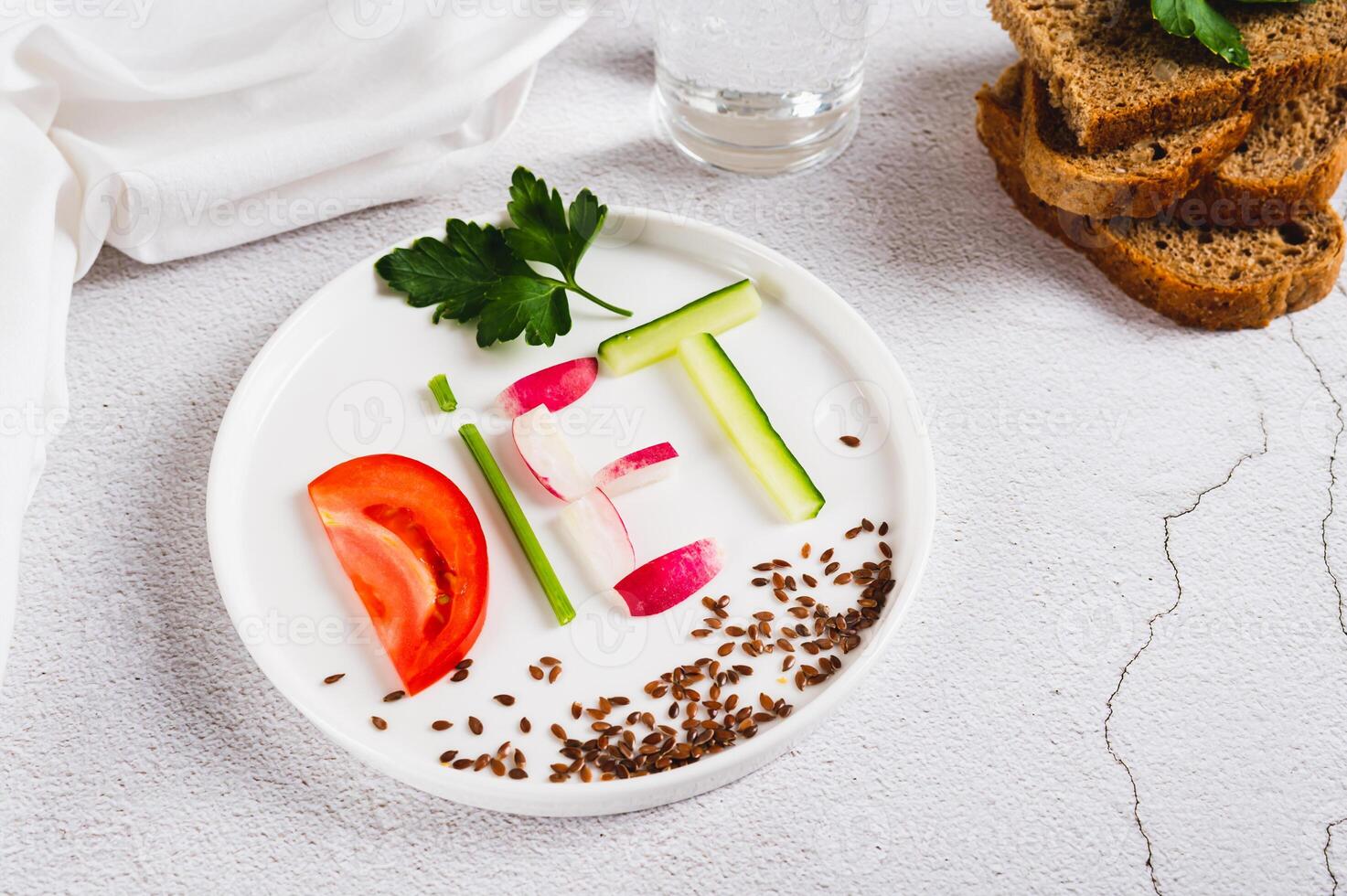 The word diet from vegetables on a plate, bread and a glass of water on the table photo