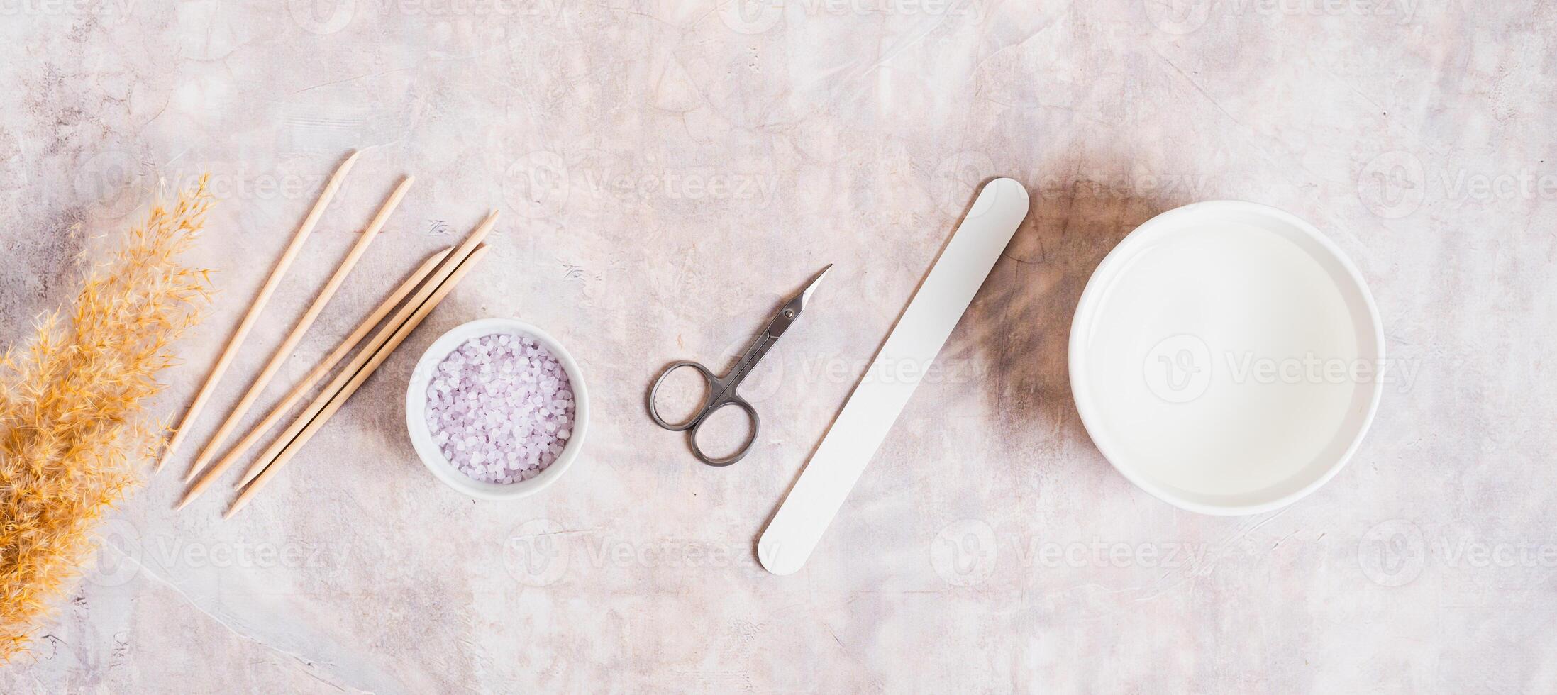 Manicure scissors, nail file, water, salt and nail sticks top view web banner photo