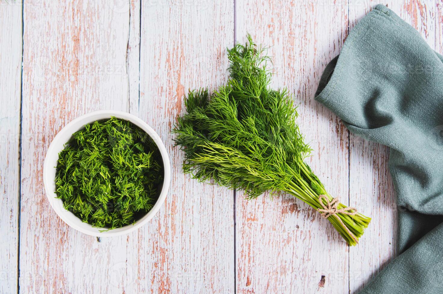 Bunch of fresh dill and chopped dill in a bowl on a table top view photo