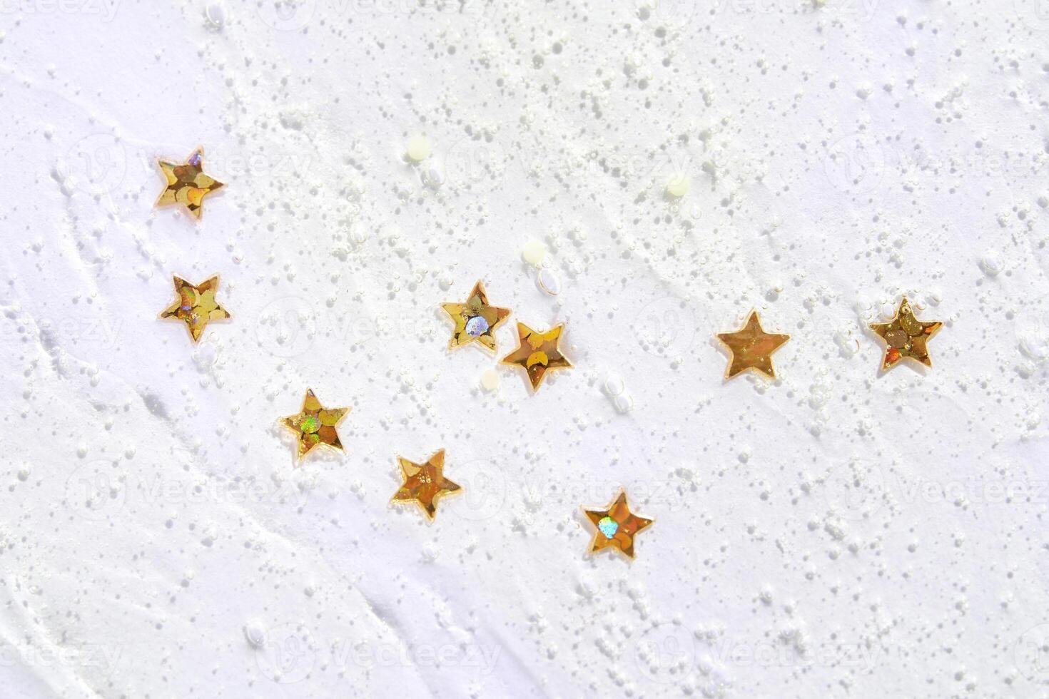 Gold star sequins on white texture creating a festive and elegant abstract pattern. photo
