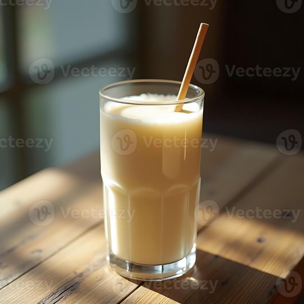 Serving of Fresh Milk in Glass with Straw on Wooden Table photo