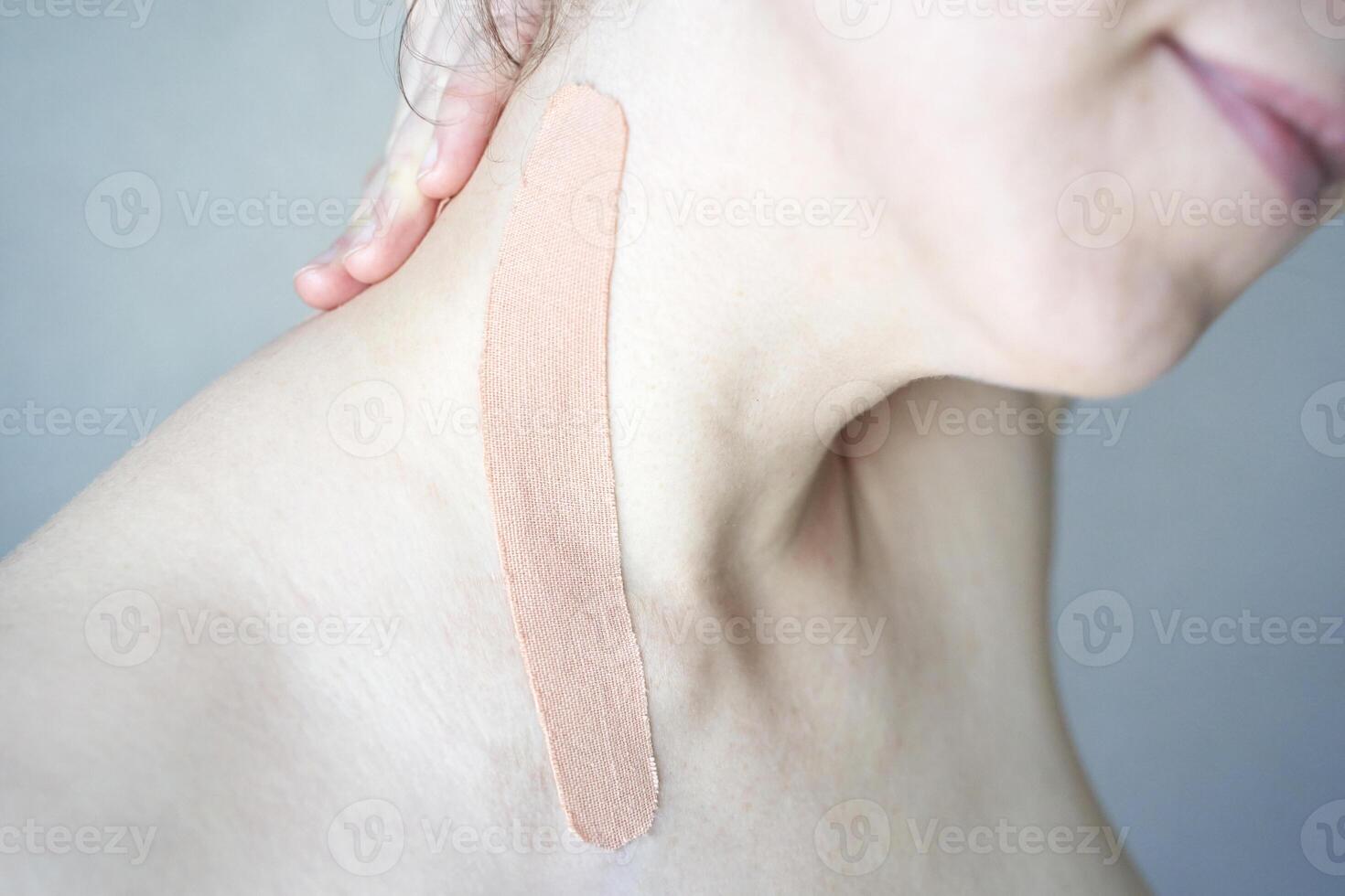 Close-up of elastic beige kinesiology tape on female caucasian shoulder for muscle support and pain relief. photo