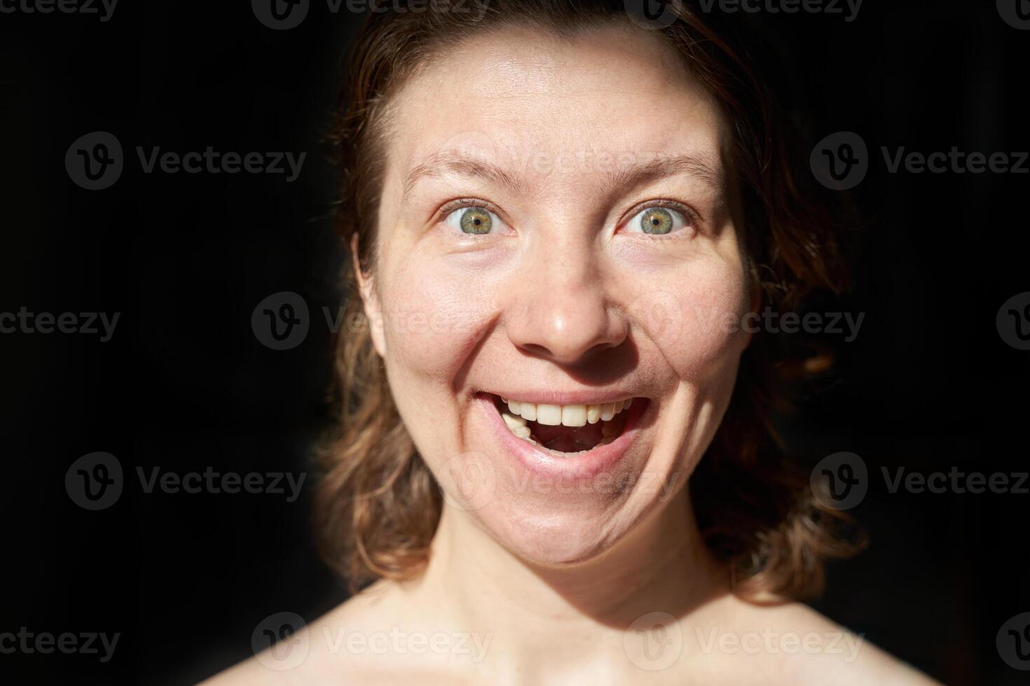 Joyful caucasian female adult with light eyes expressing happiness in close-up image. photo