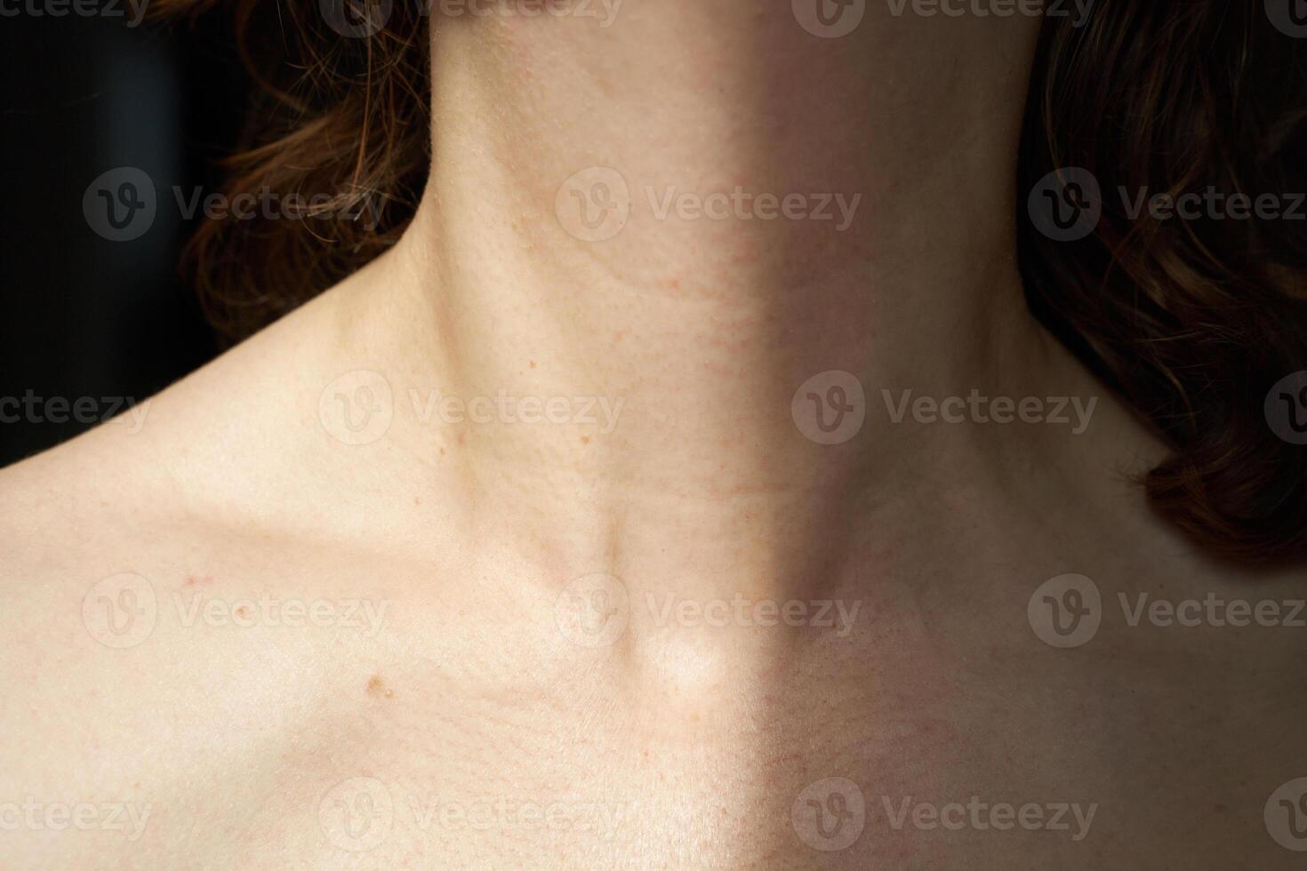Close-up of female neck and collarbone with natural light and brown curly hair. photo