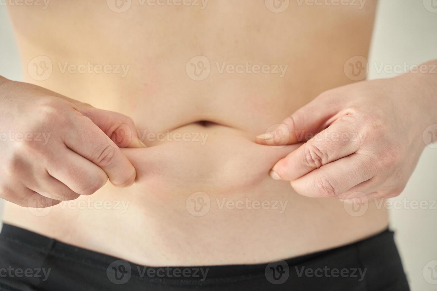 Caucasian adult demonstrating abdominal skin pinch for body fat assessment. photo