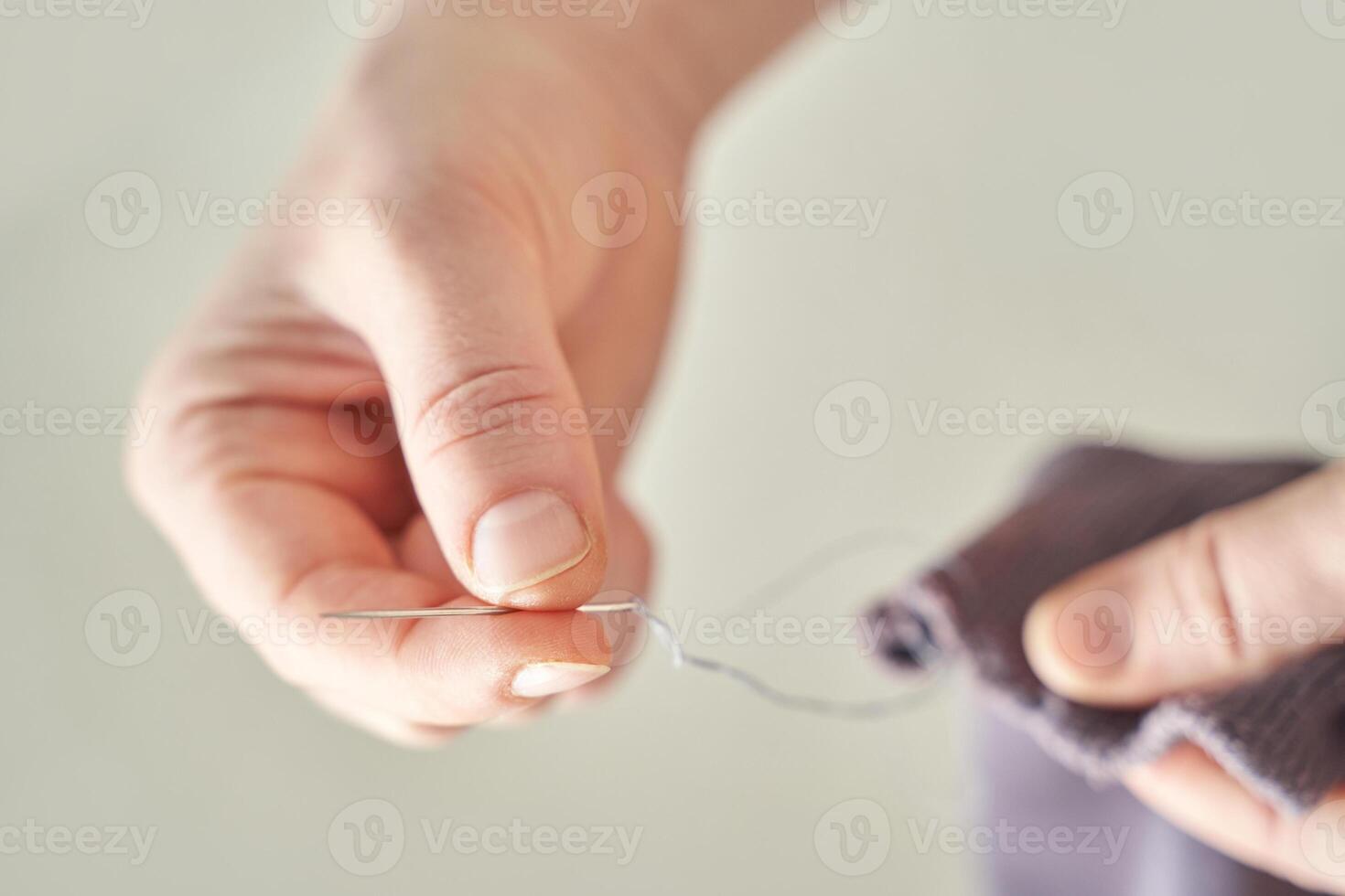 Close-up of adult caucasian female hands sewing needle and thread with fabric. photo