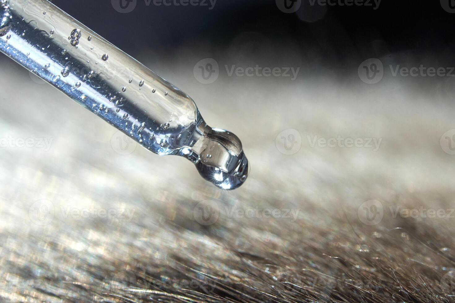 Close-up of pipette dropping liquid onto hair strands with dew drops in focus. photo