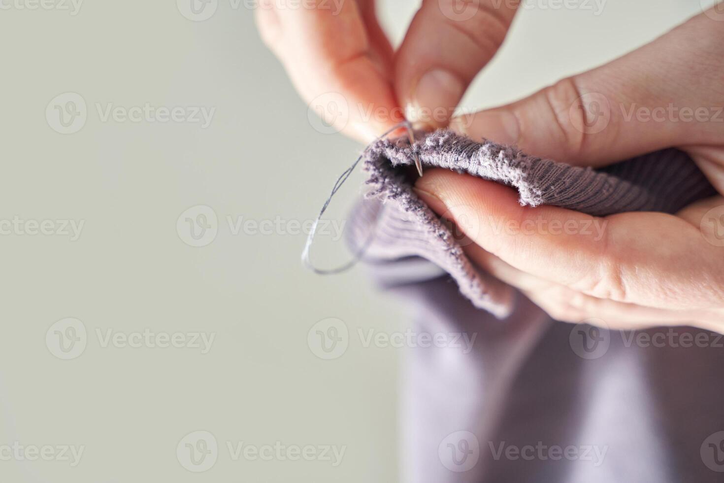 Close-up of person's hands mending purple fabric with needle and thread focus on precision and care. photo