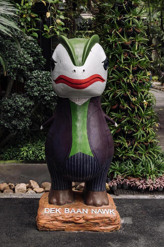 Chon Buri, Thailand - May 1, 2023 - Green and black statue of a dinosaur with a red mouth and a green cape photo