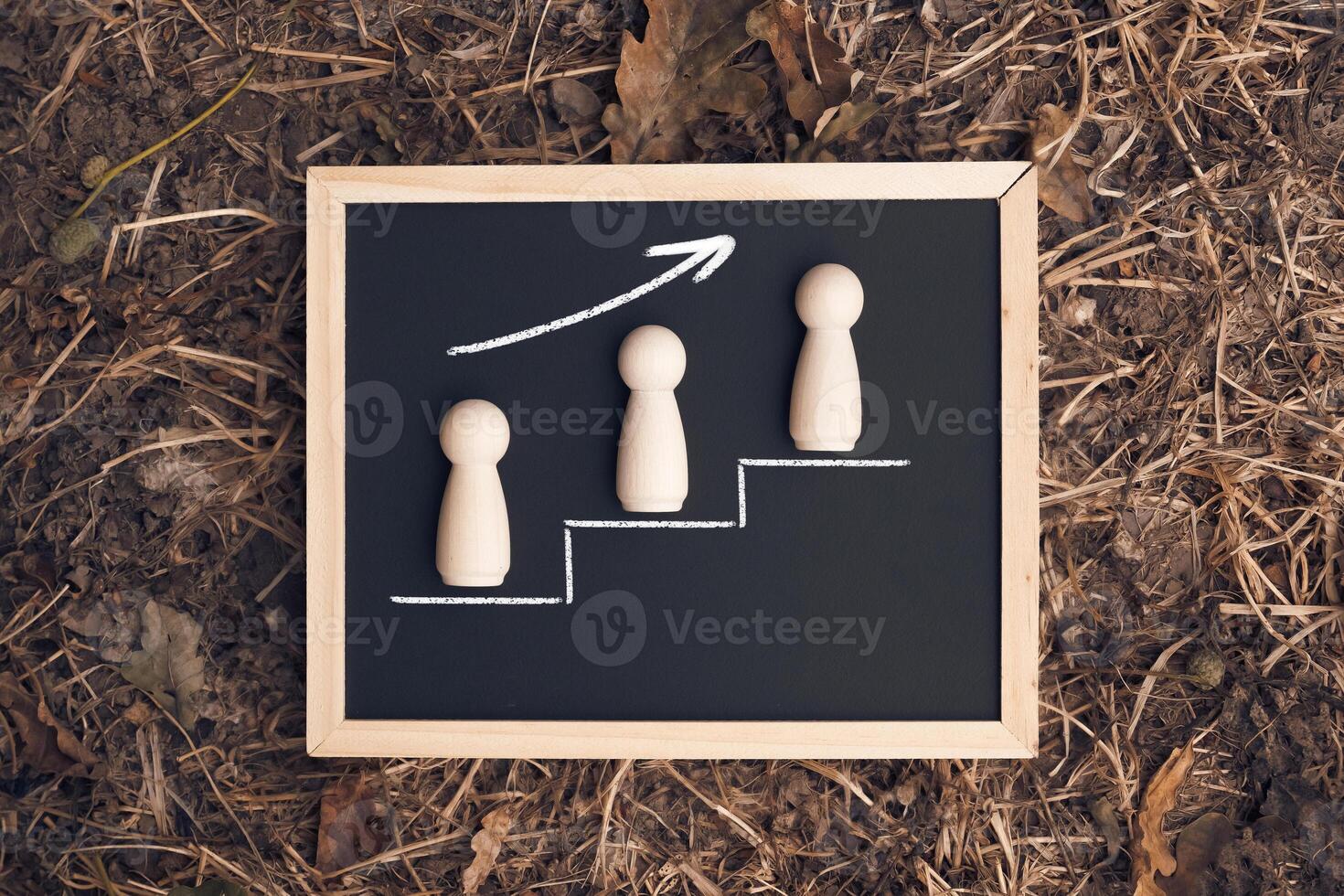 Three wooden figures are on a chalkboard with a line going up photo