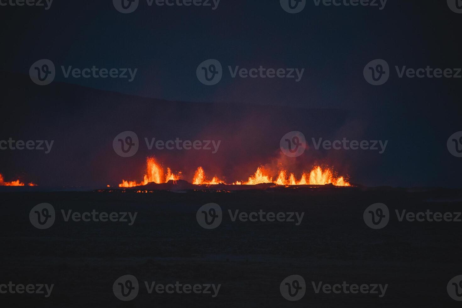 Volcanic activity in Grindavik Iceland. Bright volcanic eruptions light up the dark Icelandic night, with glowing lava fountains piercing the shadows photo
