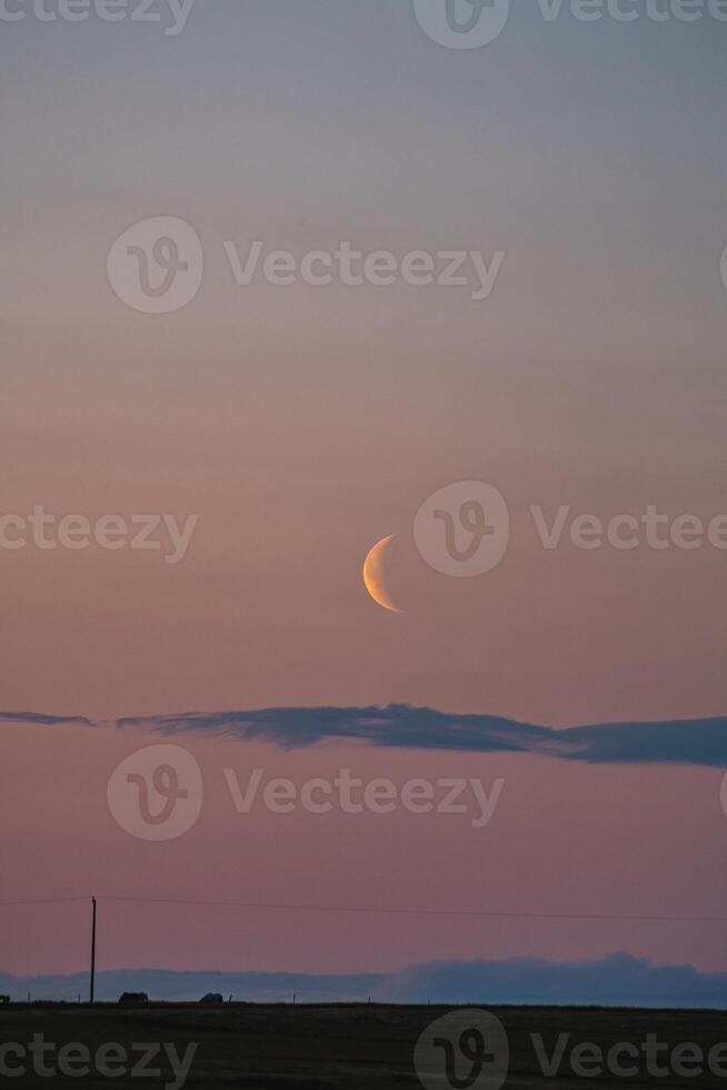 Delicate crescent moon hangs low in a pastel-colored sky, with soft hues of pink and blue blending seamlessly at dusk. Snaefellsnes peninsula, west Iceland photo