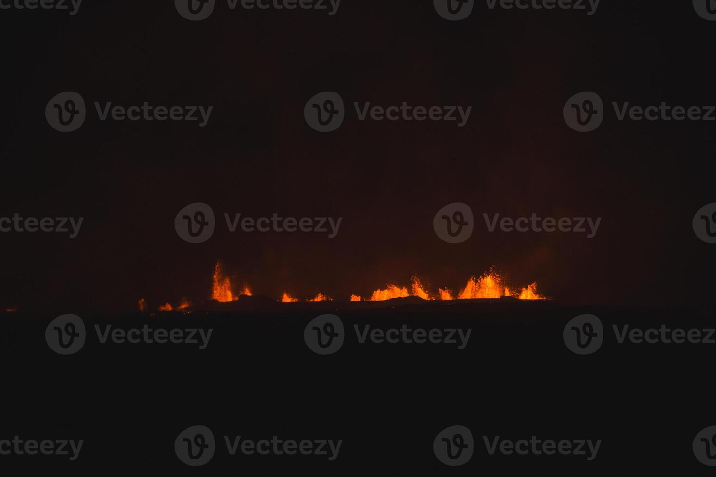 Grindavik Iceland. Bright volcanic eruptions light up the dark Icelandic night, with glowing lava fountains piercing the shadows photo