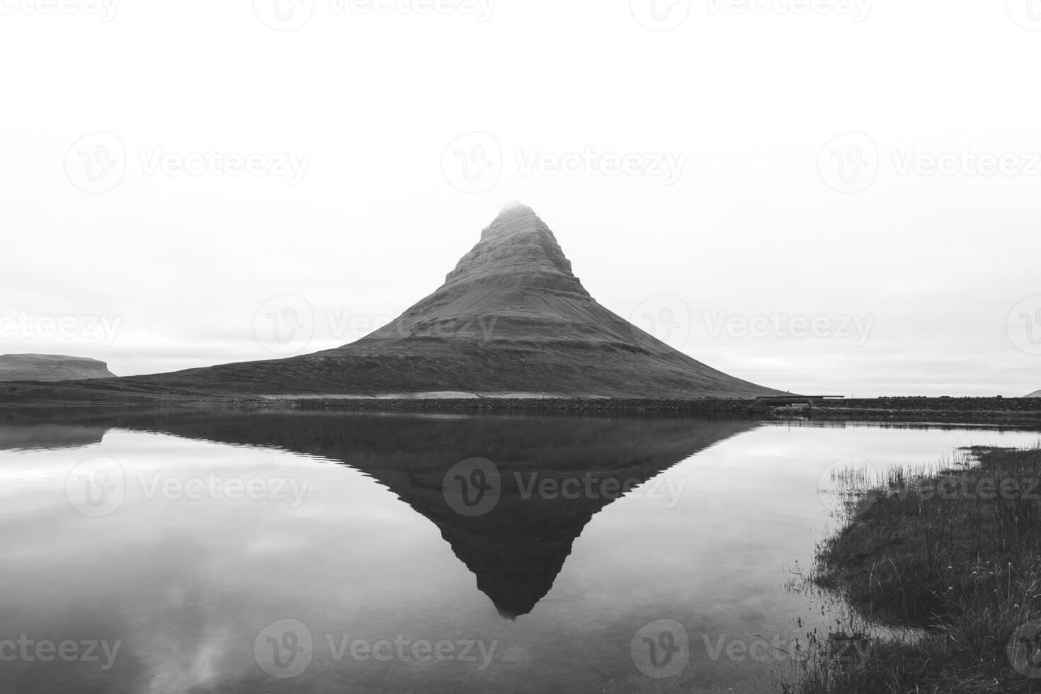 Black and white Kirkjufell, the iconic mountain on the Snafellsnes Peninsula in west Iceland, stands majestically with its reflection mirrored in the still waters below photo
