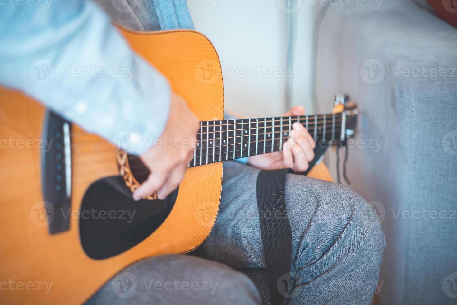 Close-up on musician strums an acoustic guitar immersed in music. His casual style, warm lighting, and relaxed atmosphere create a serene, artistic, and inspiring moment photo