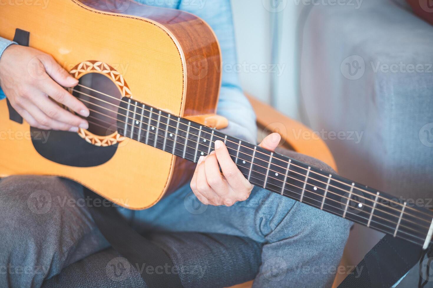 Detail on playing on guitar acoustic guitar in a cozy home, immersed in music. His casual style, warm lighting, and relaxed atmosphere create a serene, artistic, and inspiring moment photo