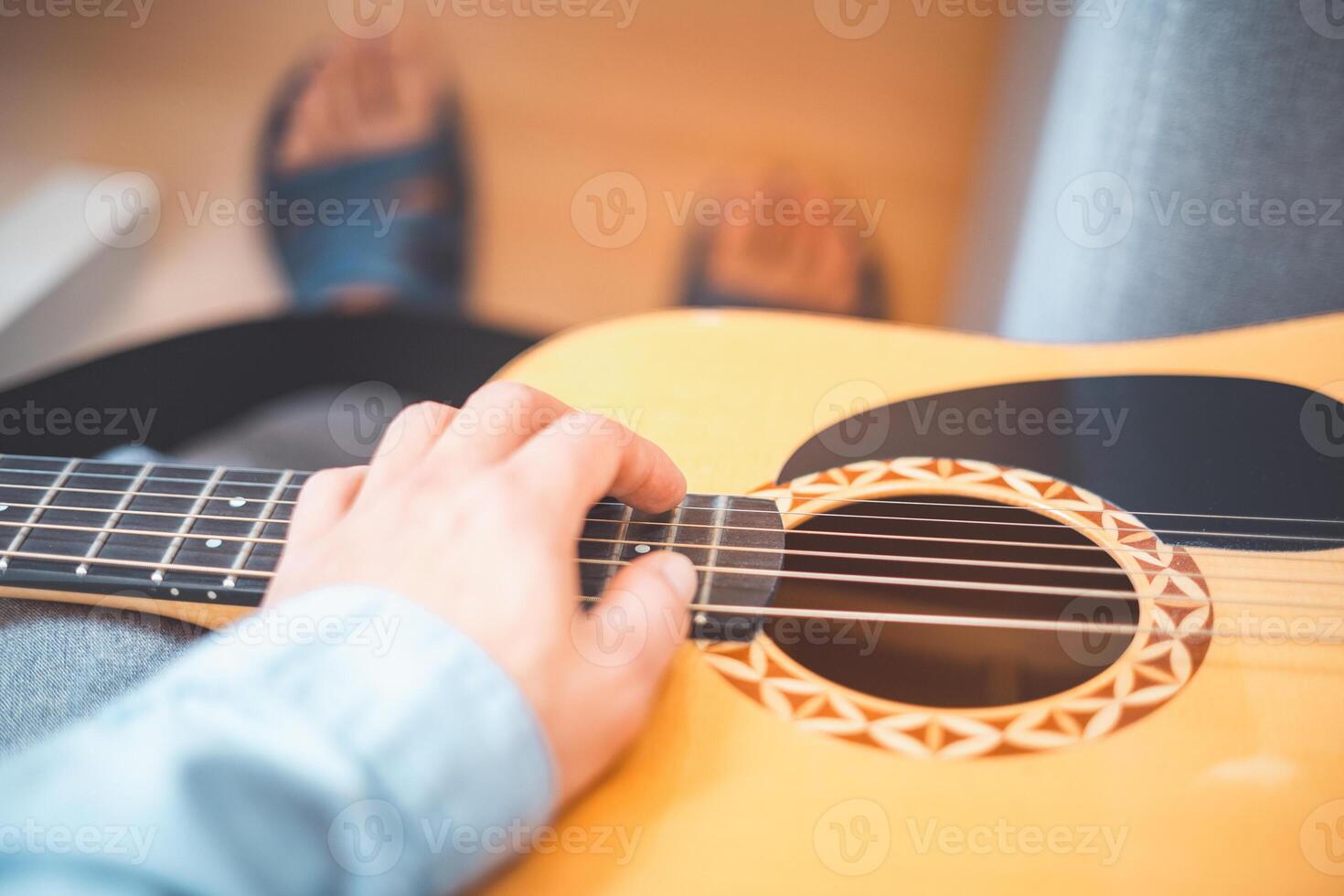 Relaxing on a cozy sofa, a man gently strums photo