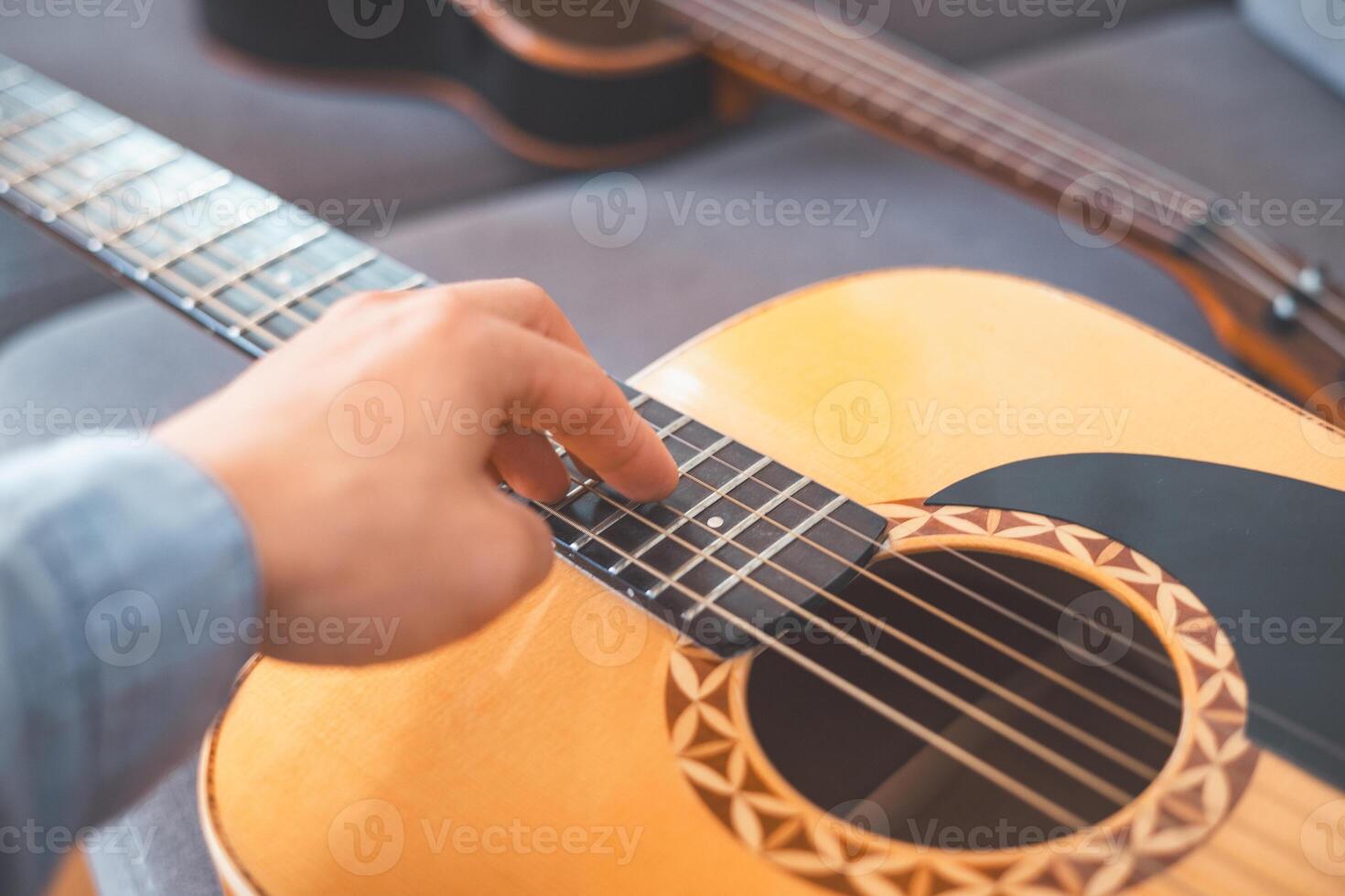 Close up gently strums his acoustic guitar, lost in music. A peaceful home setting, soft lighting, and artistic inspiration create a warm, creative atmosphere photo