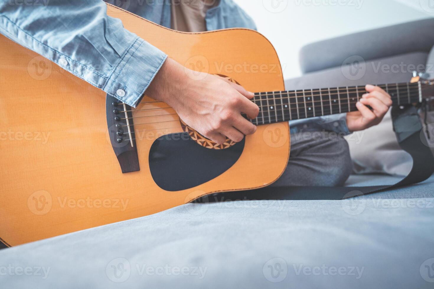 gently strums his acoustic guitar, lost in music. A peaceful home setting, soft lighting, and artistic inspiration create a warm, creative atmosphere photo