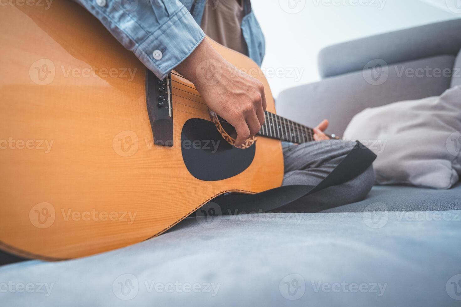 Boy gently strums his acoustic guitar, lost in music. A peaceful home setting, soft lighting, and artistic inspiration create a warm, creative atmosphere photo