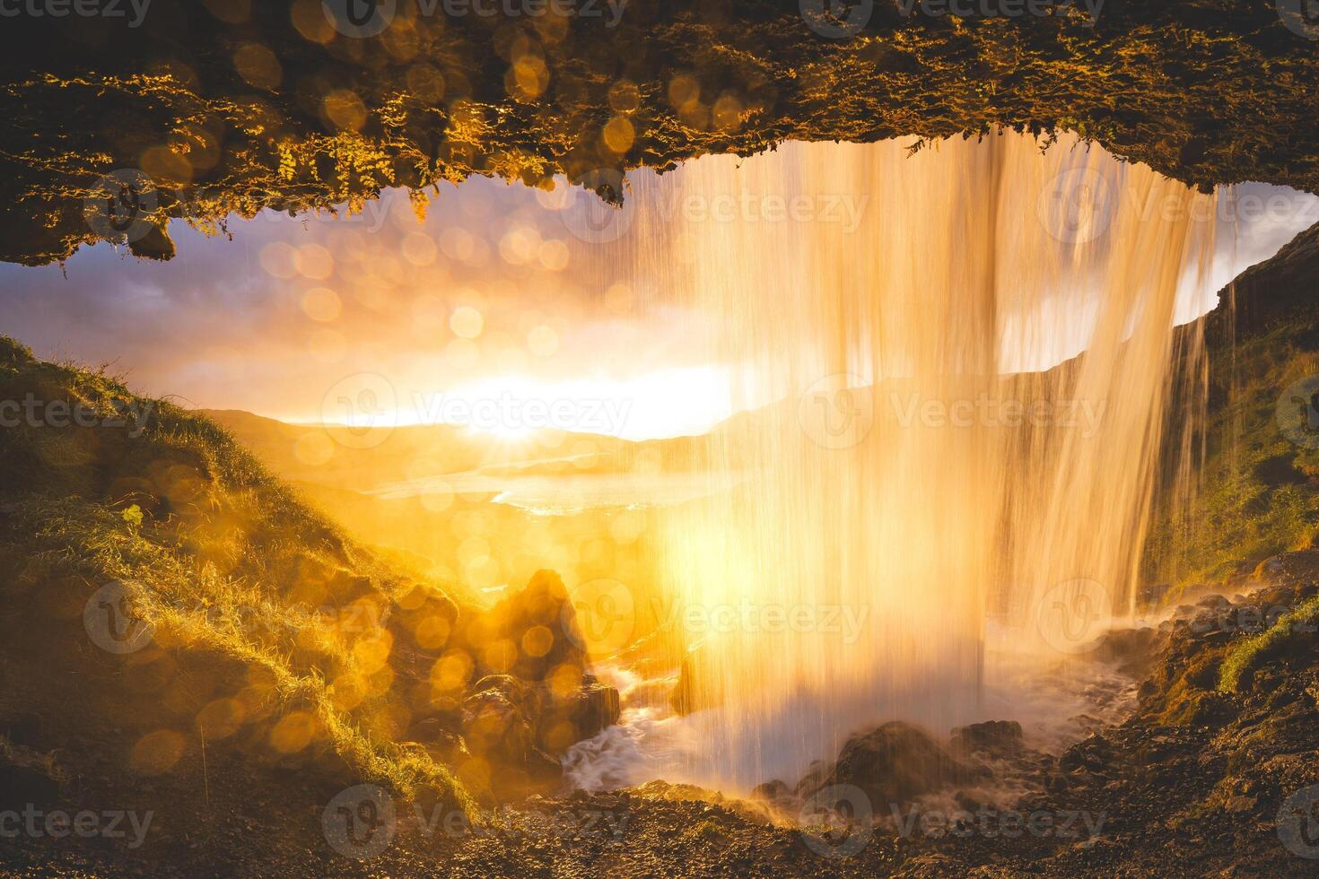 Selvallafoss waterfall on the Snaefellsnes Peninsula in western Iceland, captured from behind as cold, clear water cascades in front of a sunset photo