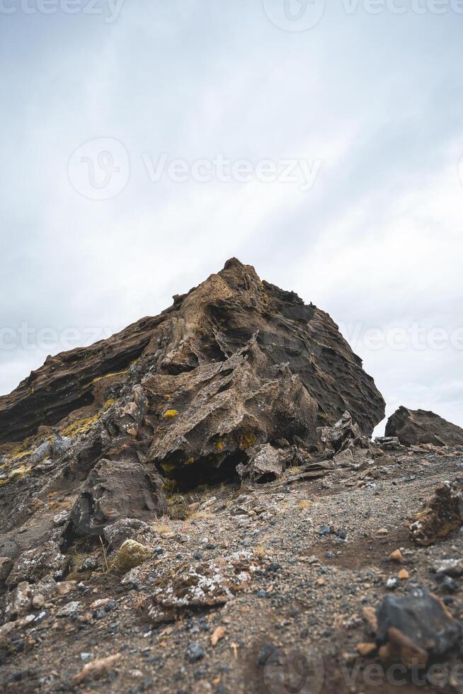 Jagged volcanic rock formation rises from Icelandic soil, sculpted by time and lava raw, ancient, and striking beneath a brooding sky photo