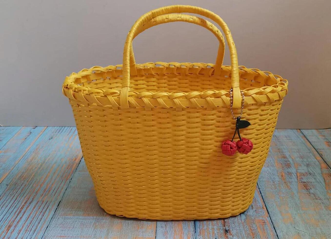 A yellow basket bag with a red handle photo