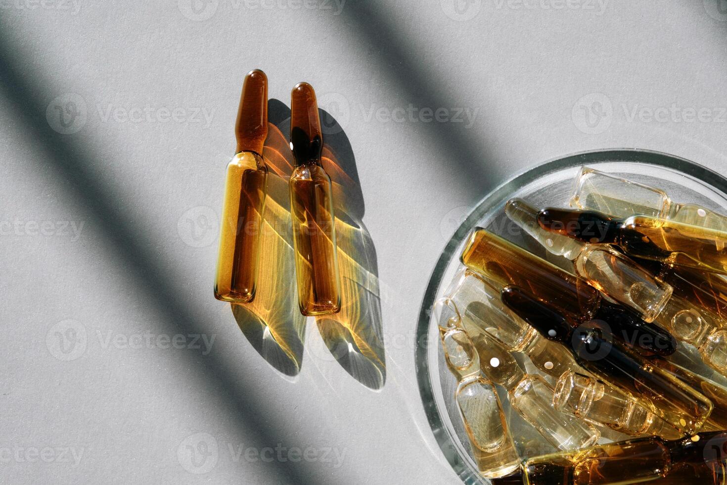 Ampoules with a medical drug on a gray background with stripes of shadows. photo