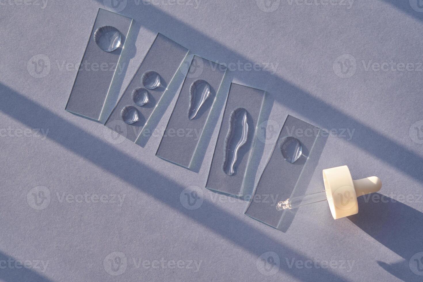 The texture of serum or micellar water on slides on a blue background with streaks of shadows. photo
