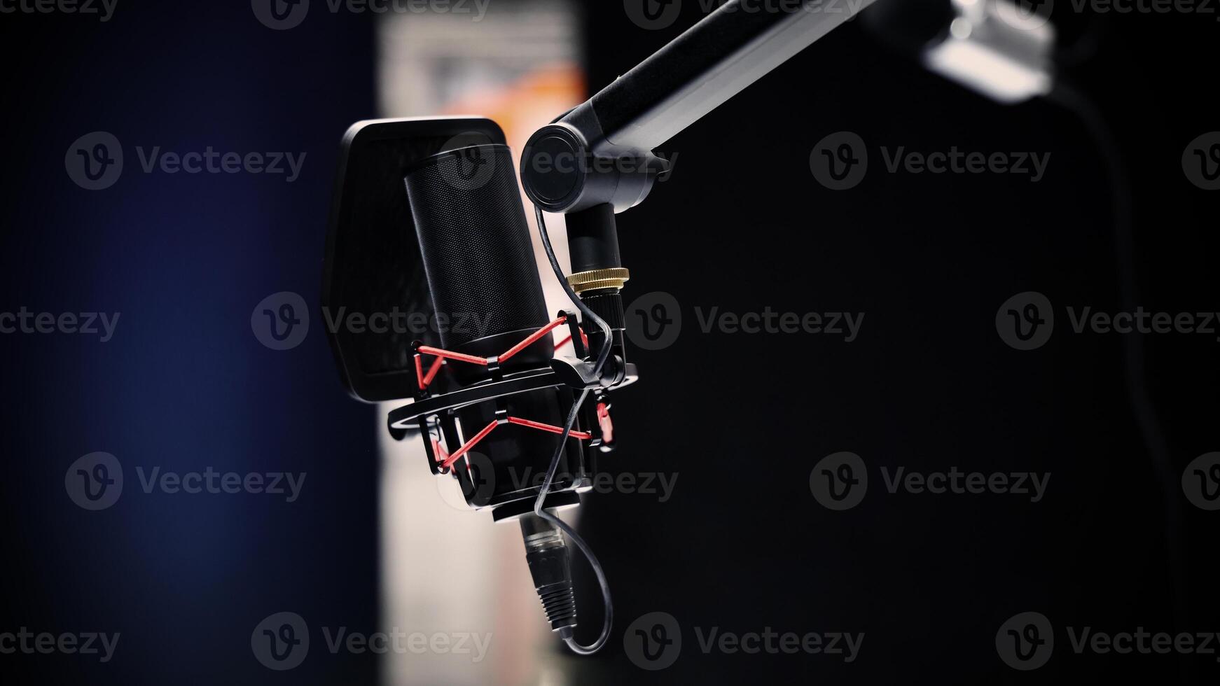 A Professional studio microphone with a pop filter is suspended boom arm and studio lights photo
