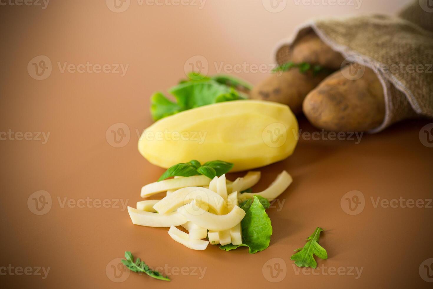 Still life with potatoes in a sack and slices on a brown background photo